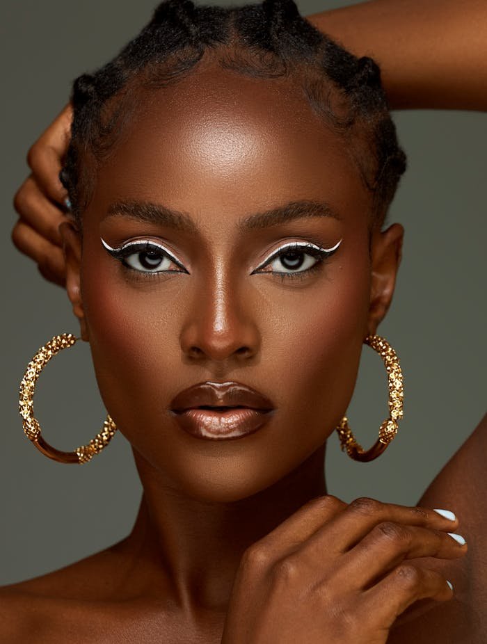 Stunning studio portrait of a woman with striking makeup and gold earrings, capturing elegance and fashion.